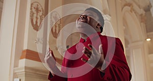 Crop view of african american male gospel singer in 30s. Young man wearing red suit putting hand on heart while singing