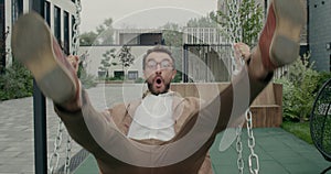 Crop view of bearded guy in glasses swinging and laughing while looking to camera. Man with neckerchief having fun while