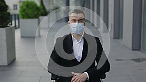 Crop view of disabled businessman in 40s wearing medical protective mask and looking to camera. Portrait of man in wheel
