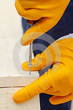 Crop view driving self-tapping screw into chipboard placed on wooden workbench