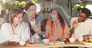 Crop view of funny guy gesturing and telling story while spending good time with coworkers. Happy young people laughing