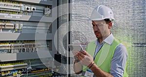 Crop view of male electrical engineer standing near therminal box of solar panel. Guy in protective helmet and uniform