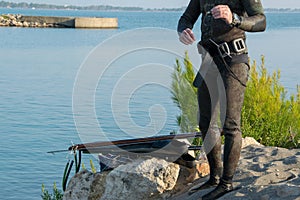 Crop view of scuba diver adult man on a seashore with spearfishing gear (fins, speargun), space for text