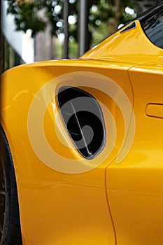 Crop view of side air intake vent scoops produced of shiny black metal placed near door. Fantastic design of yellow