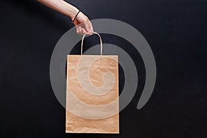 Crop view of woman hand holding craft paper shopping bag