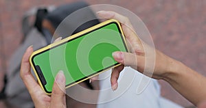 Crop view of woman using phone for playing online games while sitting at street. Female person holding smartphone with