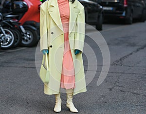 Crop woman in yellow long coat on street