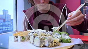 Crop young man eating sushi in restaurant
