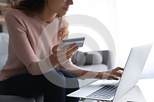 Crop of young woman use credit card shopping on laptop