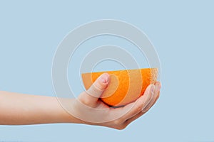 Croped half oranges in the girl`s hands isolated on blue