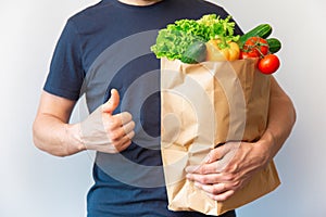 croped man with thumbs up holding paper bag with vegetable. curier doing happy thumbs up gesture with hand approving
