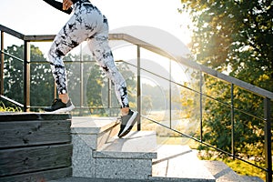 Croped view of woman running up on stone stairs at warm sunny days