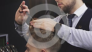 Cropepd shot of a professional barber cutting hair of his male client