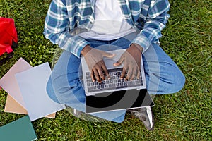 Cropped of African American man typing on laptop on lawn