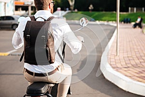 Cropped back view of man with backpack rides on motorbike