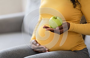 Cropped of black pregnant woman holding green apple