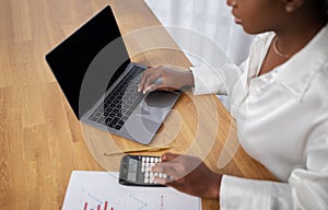 Cropped of black woman using laptop with empty screen, mockup