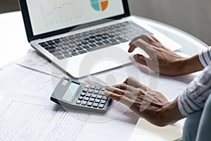 Cropped close up African American woman calculating bills, using laptop