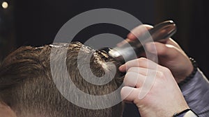 Cropped close up of a barber cutting hair of his client with a trimmer