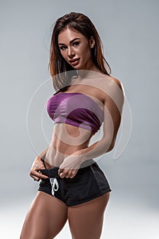 Cropped close up body of fit woman wearing shorts and sport top showing slim beautiful stomach and abs in diet fitness