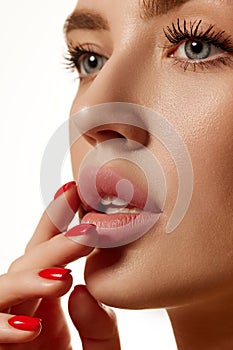 Cropped close-up image of beautiful female face with plump lips, nude lipsticks makeup isolated against white studio