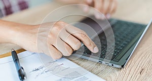 Cropped close-up image of a businessman`s hands typing working on a laptop at the home office. Freelancer, remote occupation,