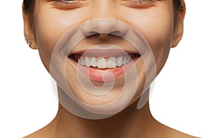 Cropped close-up image of female lips, cheecks and nose isolated over white studio bacground. Perfect healthy smile