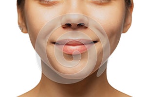 Cropped close-up image of female lips, cheecks and nose isolated over white studio bacground. Smiling beauty