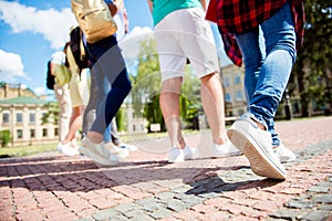 Cropped close up low angle photo shot of six student`s legs, walking on the cobbles. Sunny spring day, students are going to camp