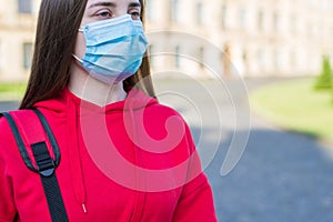 Cropped close up photo of minded pondering pensive teen girl wearing casual clothes using surgical mask outside