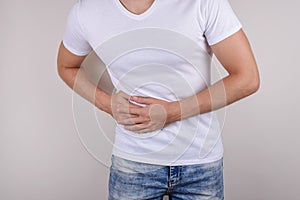 Cropped close up photo portrait of unhappy sad upset guy holding touching right side wearing casual t-shirt denim trousers isolate