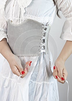 close-up shot of a lady dressed in a white dress with a wide grey leather belt or corset