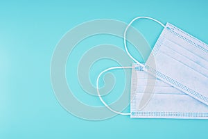 Cropped close-up of two disposable medical face masks on a blue background, flat lay, copy space. Means of personal protection