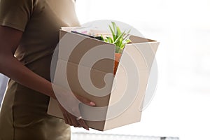 Cropped closeup image african female holding carton box with belongings