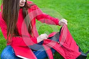 Cropped closeup photo of confident clever intelligent beautiful girl packing unwrapping stuff into in the satchel sitting on grass