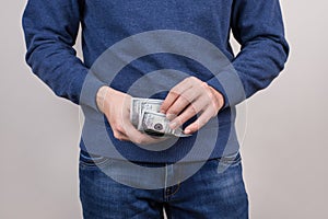 Cropped closeup photo of confident guy in blue sweater pullover jumper holding stack pile of money in hands wearing denim clothes