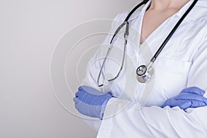 Cropped closeup photo of professional doctor in nitrile gloves standing with folded crossed arms isolated over grey background