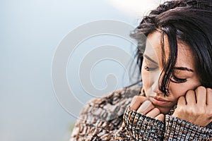 Cropped closeup shot of dreamy beautiful female wearing cozy sweater posing against the lake. Portrait of romantic female with