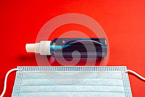 Cropped disposable mask with hand sanitizer on red background