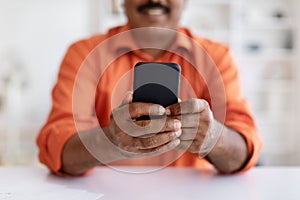 Cropped of eastern man sitting at table, using cell phone