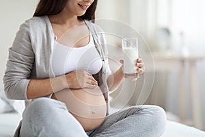 Cropped of expecting lady with big tummy drinking milk