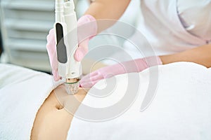 Cropped of female cosmetologist doing microneedle rf lifting of woman belly skin