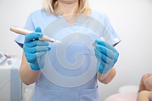 Cropped female doctor in blue attire holding dermapen needle and ampoule for mesotherapy technology. Spa beauty clinic photo