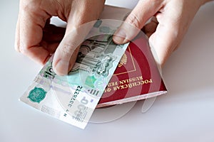 Cropped female hands holding russian international passport and paper money, rubles