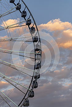 Cropped Ferris wheel and sunset lit clouds in the background