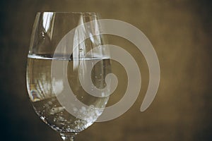 Cropped glass of white wine on a rustic wooden brown background. rest, holiday, party. alcoholic drink closeup. copy space