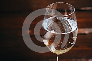 Cropped glass of white wine on a rustic wooden brown background. rest, holiday, party. alcoholic drink closeup. copy space