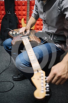 Cropped guitar player setting tone to his music instrument