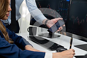 Cropped hand of businessman showing stock market on phone to woman. Infobahn.