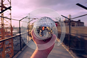 Cropped hand holding a disco ball outdoors